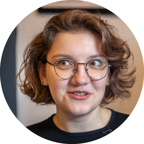 Young lady with wire-rimmed spectacles testimonial head shot.